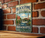 A vintage metal sign on a brick wall, featuring an illustration of a river and a bridge, with the text "John H. Chaffee Blackstone River Valley National Heritage Corridor" and "Massachusetts Our Heritage - Our Community - Our Future".