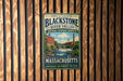A vintage metal sign for the Blackstone River Valley National Heritage Corridor in Massachusetts, featuring a scenic image of a river and buildings.