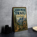 A vintage-style metal sign for the John Muir Trail in California, featuring a scenic mountain landscape and a trail marker.