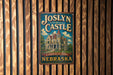 A vintage-style metal sign for "Joslyn Castle" in Nebraska, featuring an illustration of a castle-like building surrounded by trees.