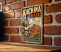 A vintage metal sign with the text "KACHINA TRAIL" and "Discover the Spirit of Arizona" is displayed on a brick wall.