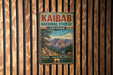 A vintage metal sign for the Kaibab National Forest in Arizona, featuring a scenic mountain landscape.