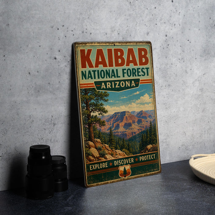 A vintage-style metal sign for Kaibab National Forest in Arizona, featuring a scenic mountain landscape and the text "EXPLORE • DISCOVER • PROTECT".