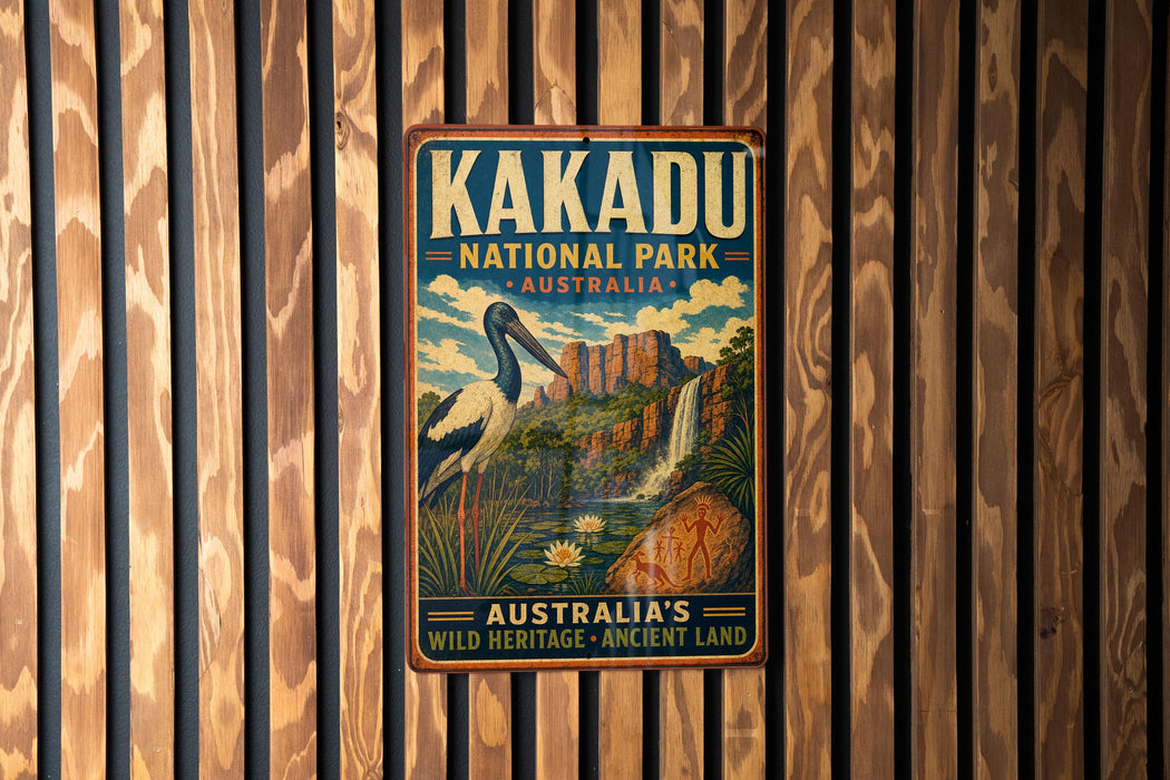 A vintage-style metal sign for Kakadu National Park in Australia, featuring a bird and a waterfall, is displayed on a wooden wall.