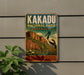 A vintage-style metal sign for Kakadu National Park in Australia, featuring an illustration of a bird and a landscape with mountains and water.