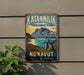 A vintage-style metal sign for Katanningik Territorial Park, featuring a scenic landscape with mountains, a lake, and a rock formation.