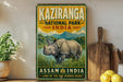 A vintage-style sign for Kaziranga National Park, India, featuring an illustration of a rhinoceros in a grassy field with mountains in the background.
