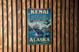 A vintage metal sign for Kenai Fjords, Alaska, featuring a whale and mountains in the background.