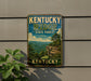 A vintage-style sign for Kentucky Ridge State Forest, featuring a scenic mountain landscape with a cliff and trees.