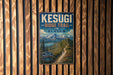 A vintage metal sign for the Kesugi Ridge Trail in Alaska, featuring a scenic mountain landscape with a winding trail.