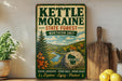 A vintage-style metal sign for Kettle Moraine State Forest in Wisconsin, featuring a scenic landscape with a river, pine trees, and autumn foliage.