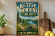 A vintage-style sign for the kettle moraine State Forest in Wisconsin, featuring a scenic landscape with a river, pine trees, and a winding path.