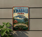a vintage metal sign with a mountain landscape and tropical flowers, mounted on a wall.