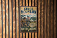 A vintage metal sign for Kings Mountain National Military Park in South Carolina, featuring an illustration of soldiers and an American flag.