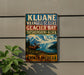 A metal sign with text and a picture of a moose in a mountainous landscape, mounted on a wall.