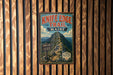 A vintage metal sign for Knife Edge Trail in Maine, featuring a mountain landscape and trail information.