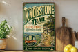 A vintage-style sign for Knobstone Trail in Indiana, featuring a scenic mountain landscape with a trail leading up to a cliff.