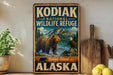 A vintage-style sign for the Kodiak National Wildlife Refuge in Alaska, featuring a bear and an eagle in a mountainous landscape.