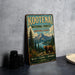 A vintage-style metal sign for Kootenai National Forest, Montana and Idaho, featuring a scenic image of a bear in the foreground with mountains and pine trees in the background.