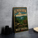 A vintage-style metal sign for Kumbarow State Forest, featuring a scenic landscape with a river and mountains, is displayed on a gray countertop.