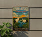 A vintage-style metal sign advertising the Kushiro-Shitsugen, a famous Japanese nature reserve, featuring two cranes in a serene landscape.