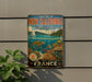 A vintage-style metal sign advertising the Lagoon of New Caledonia, featuring a seascape with a sailboat, coral reefs, and marine life.