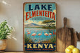 A vintage-style sign for Lake Elmenteita, the bird-watching destination in Kenya, featuring a scenic landscape with flamingos and mountains in the background.