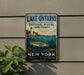 A vintage-style metal sign for Lake Ontario National Marine Sanctuary, featuring a lighthouse, a fish, and a sailboat, mounted on a wall.