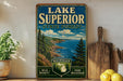 A vintage-style sign for Lake Superior State Forest in Michigan, featuring a scenic landscape with pine trees, cliffs, and a lake.