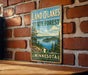 A vintage-style sign for the Land O'Lakes State Forest in Minnesota, featuring a scenic landscape with pine trees, a lake, and mountains.