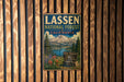 A vintage-style metal sign for the Lassen National Forest in California, featuring a scenic mountain landscape with a lake and pine trees.