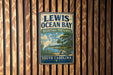 A metal sign with the text "LEWIS OCEAN BAY HERITAGE PRESERVE SOUTH CAROLINA" is displayed on a wooden fence.