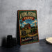 a vintage-style metal sign with a farm scene and a tractor, placed on a countertop next to some black camera lenses.