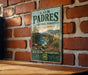 A vintage-style metal sign for the Los Padres National Forest in California, featuring a scenic landscape with mountains, trees, and a river.