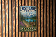 A vintage metal sign for the Lost Lake Trail in Alaska, featuring a scenic mountain landscape with a lake and pine trees.