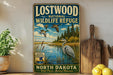 A vintage-style metal sign for Lostwood National Wildlife Refuge in North Dakota, featuring an illustration of ducks and a heron in a natural setting.