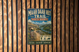 A vintage trail sign for the Maah Daha Hey Trail in North Dakota, featuring a scenic mountain landscape and inviting visitors to explore, discover, and adventure.
