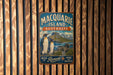 A vintage metal sign for Macquarrie Island, Australia, featuring a penguin and a seal, is displayed on a wooden wall.