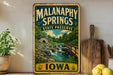 A vintage-style metal sign for Malanaphy Springs State Preserve, featuring a scenic illustration of a waterfall and a bridge surrounded by lush greenery.
