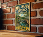 A vintage metal sign for Malanaphy Springs State Preserve in Iowa, featuring a scenic illustration of a waterfall and a bridge.