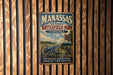 a vintage metal sign with the text "MANASSAS NATIONAL BATTLEFIELD PARK VIRGINIA" and an illustration of a cannon and soldiers in a field.