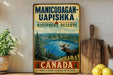 A vintage-style sign for the Manicouagan-Uapishka Biosphere Reserve in Canada, featuring a moose and a scenic landscape.