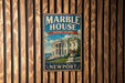 A vintage-style metal sign for the Marble House in Newport, Rhode Island, featuring an illustration of the historic building and the text "A NATION'S TREASURE NEWPORT".