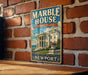 A vintage-style metal sign for the Marble House in Rhode Island, featuring an illustration of the White House and the text "A NATION'S TREASURE NEWPORT".