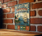 A vintage-style metal sign for the Maritime Washington National Heritage Area in Washington, featuring a lighthouse, a ship, and mountains in the background.
