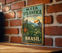 A vintage-style metal sign with a tropical landscape and two birds, mounted on a brick wall.