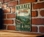 A vintage-style metal sign for the Michaux State Forest in Pennsylvania, featuring a scenic landscape with pine trees and a lake.