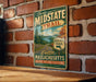 A vintage midstate trail sign is displayed on a brick wall, promoting the scenic midstate trail and encouraging visitors to explore the state.