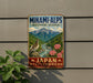 a vintage-style metal sign with a mountain landscape and a bird perched on a rock, mounted on a wall.