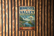 A vintage-style metal sign for the Minnesota Valley National Wildlife Refuge, featuring an illustration of a bird and a river, mounted on a wooden wall.